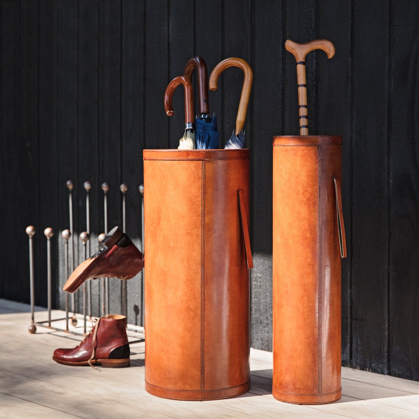 Classic tan leather entrance hall set combining a tall slim stick stand and wider shorter umbrella stand with drip tray. Ideal as a gift for a new home or office.