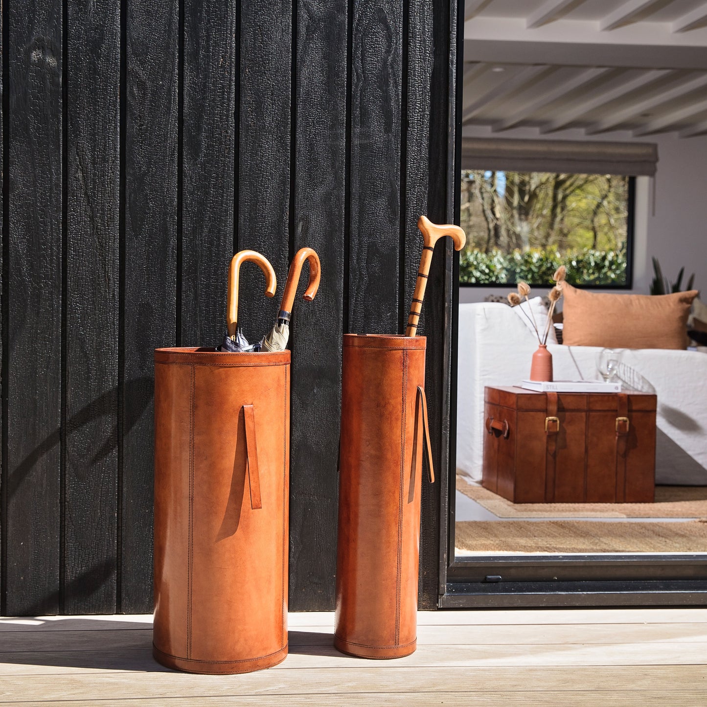 Classic tan leather entrance hall set combining a tall slim stick stand and wider shorter umbrella stand with drip tray. Ideal as a gift for a new home or office.