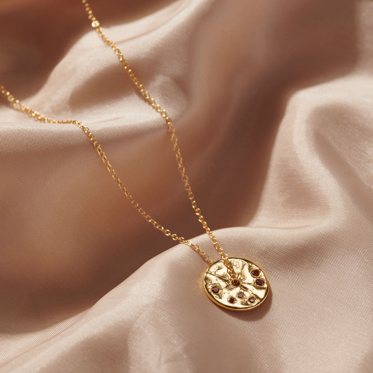 
                  
                    Gorgeous garnets set into a gold disc pendant on gold chain, the ideal gift for a January birthstone gift.
                  
                