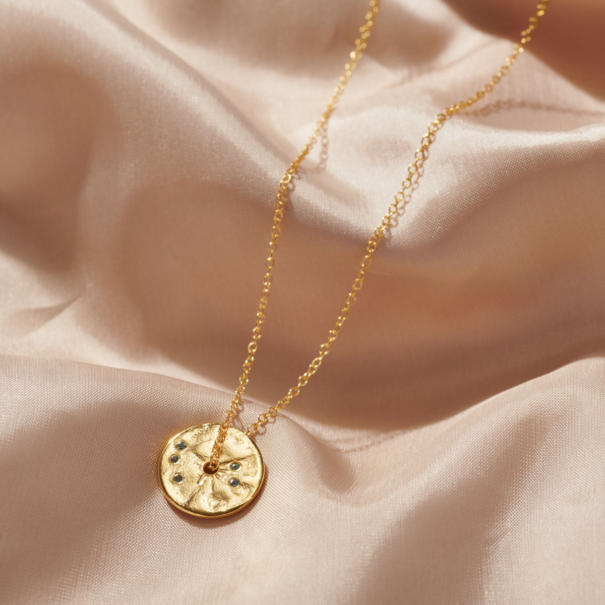 Pretty round gold disc with small set alexandrites by Claudetter Worters. Perfect gift for a June birthday.