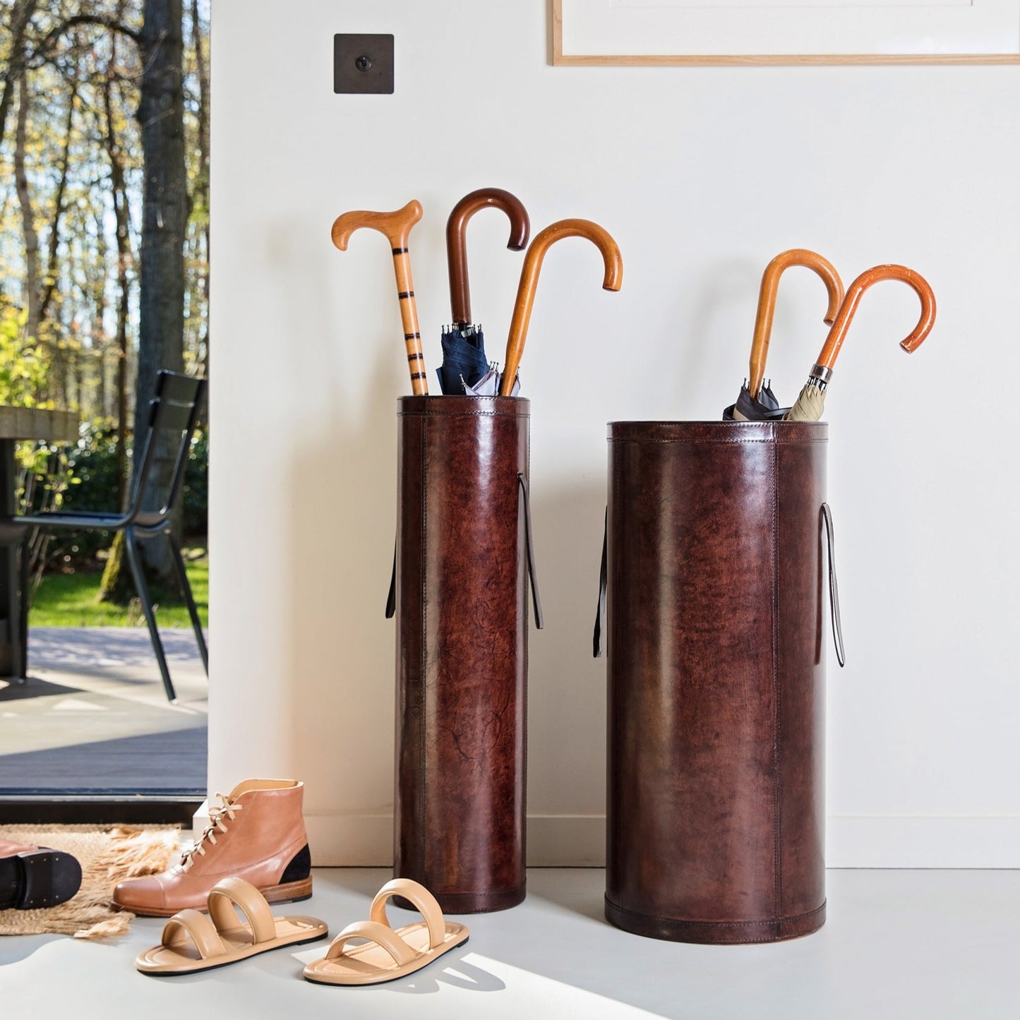 Classic brown leather entrance hall set combining a tall slim stick stand and wider shorter umbrella stand with drip tray. Ideal as a gift for a new home or office.