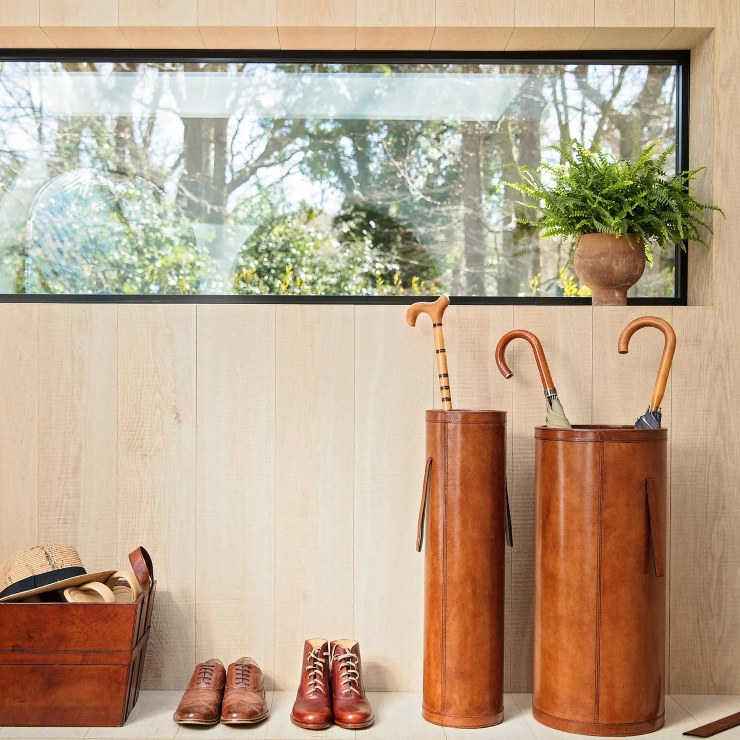 Classic tan leather entrance hall set combining a tall slim stick stand and wider shorter umbrella stand with drip tray. Ideal as a gift for a new home or office.