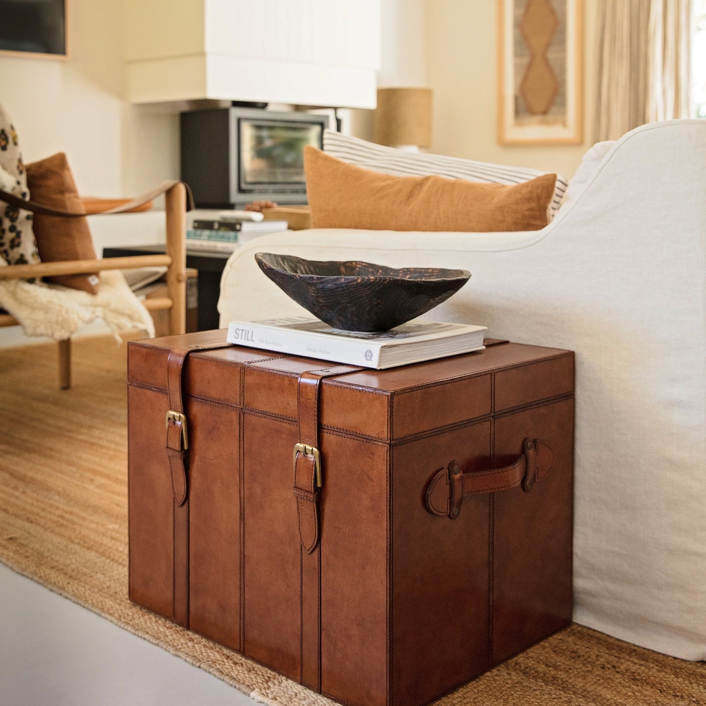 Tan leather storage trunk coffee table with buckles. Sit beside a favourite chair to use as a side table with storage for photo albums and board games. Personalise as a thoughtful new home gift.