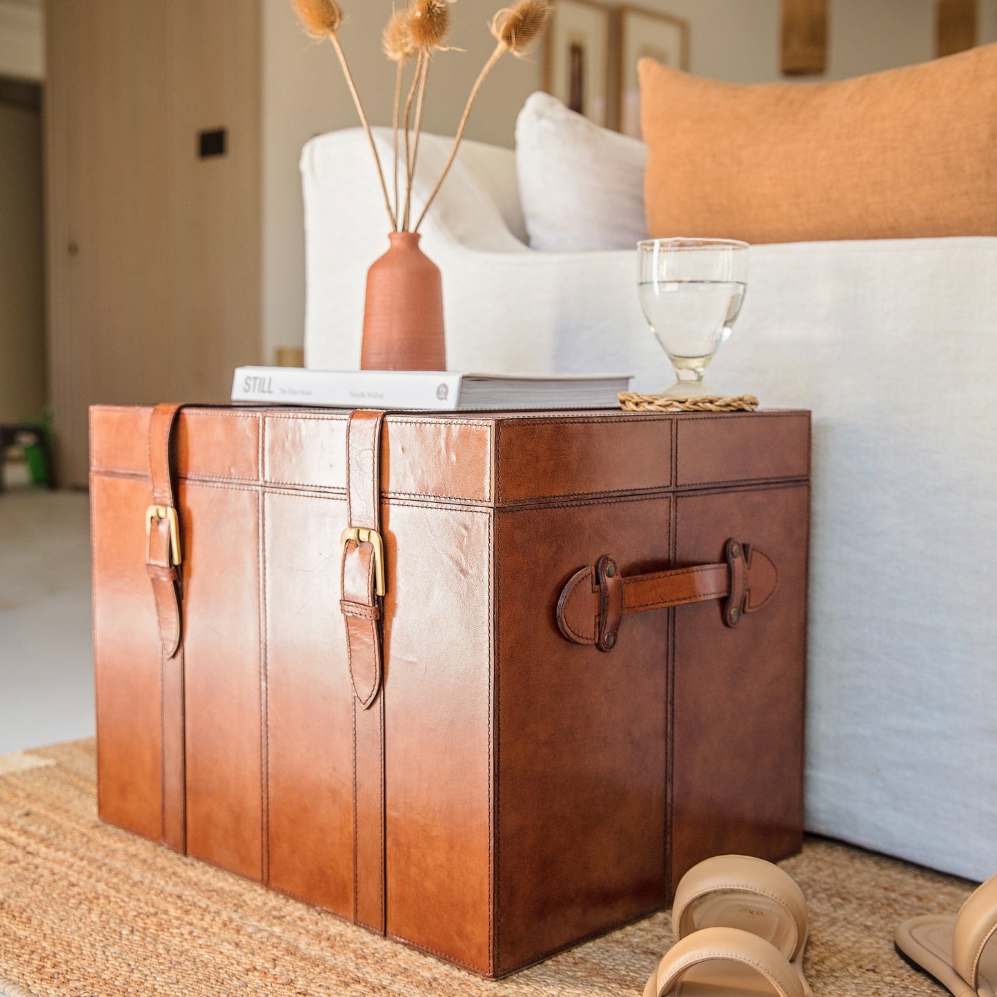 Tan leather storage trunk coffee table with buckles. Sit beside a favourite chair to use as a side table with storage for photo albums and board games. Personalise as a thoughtful new home gift.