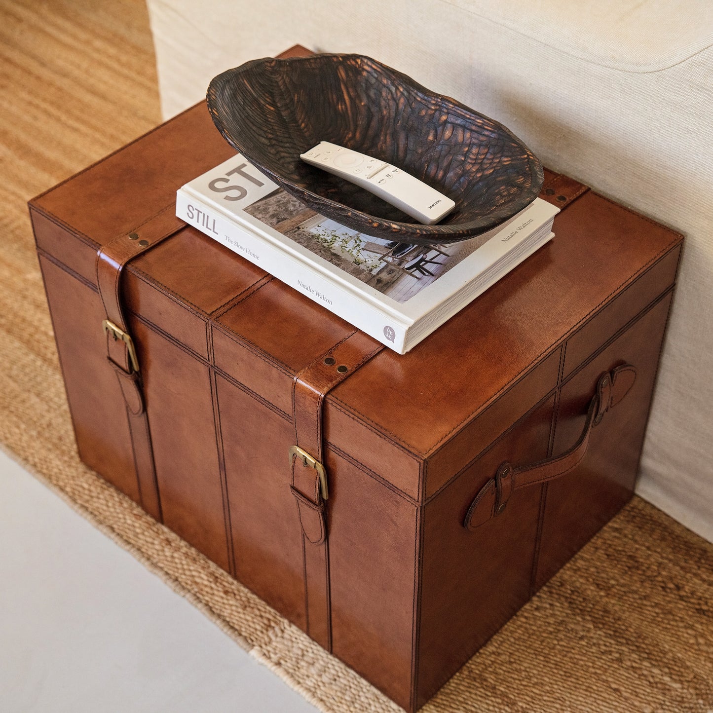 Tan leather storage trunk coffee table with buckles. Sit beside a favourite chair to use as a side table with storage for photo albums and board games. Personalise as a thoughtful new home gift.