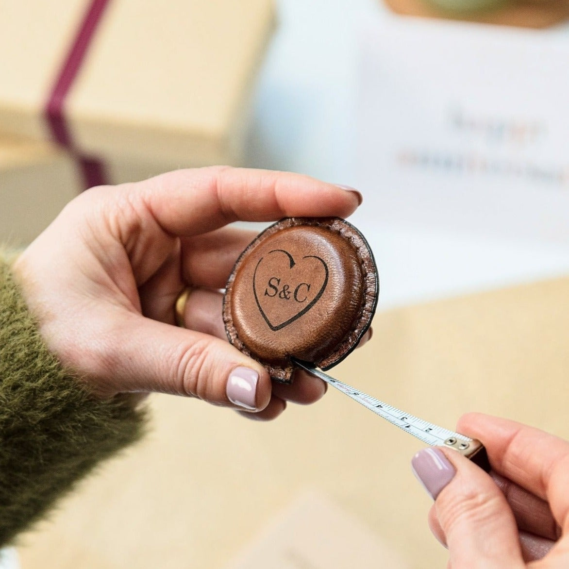 leather tape measure extended with love heart and initials engraved on leather case