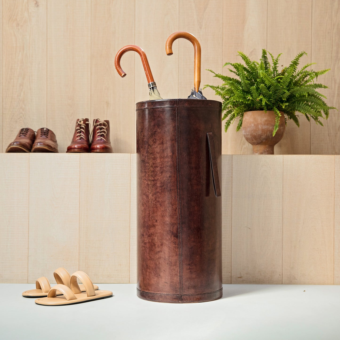 leather umbrella stand in brown leather with carry straps and storing 2 umbrellas in hallway