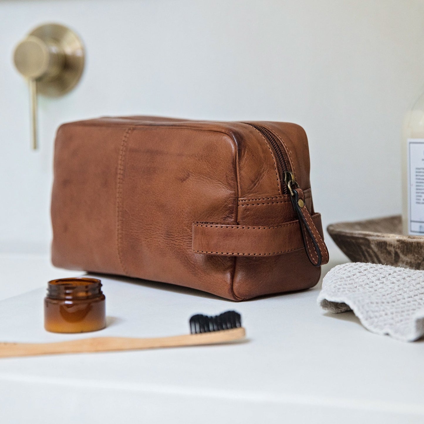 Men’s leather wash bag in soft, supple tan leather, with inside pocket and carry handle. Personalise with initials or a name as a thoughtful leather anniversary gift for him.