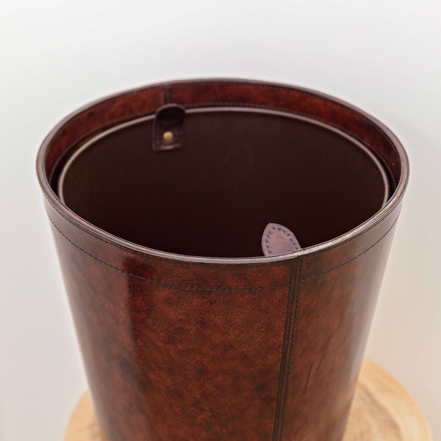 Round leather waste paper bin with removable metal liner for use in the home or office.