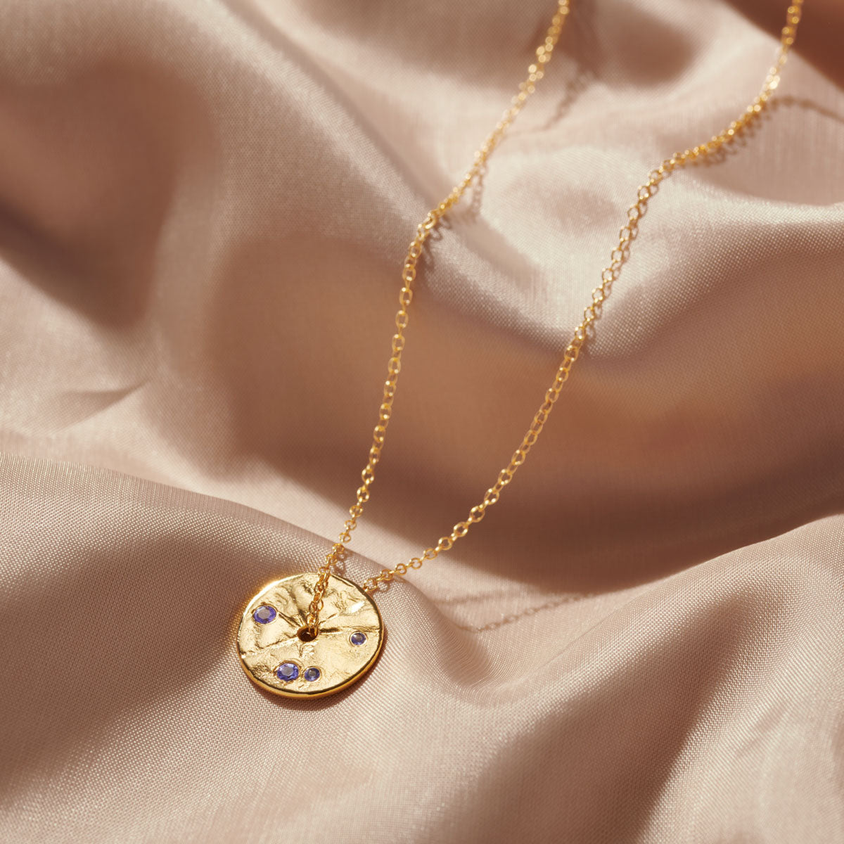 Tanzanite gemstones set into gold spinning disc pendant on fine gold chain. Ideal gift for a December birthday.