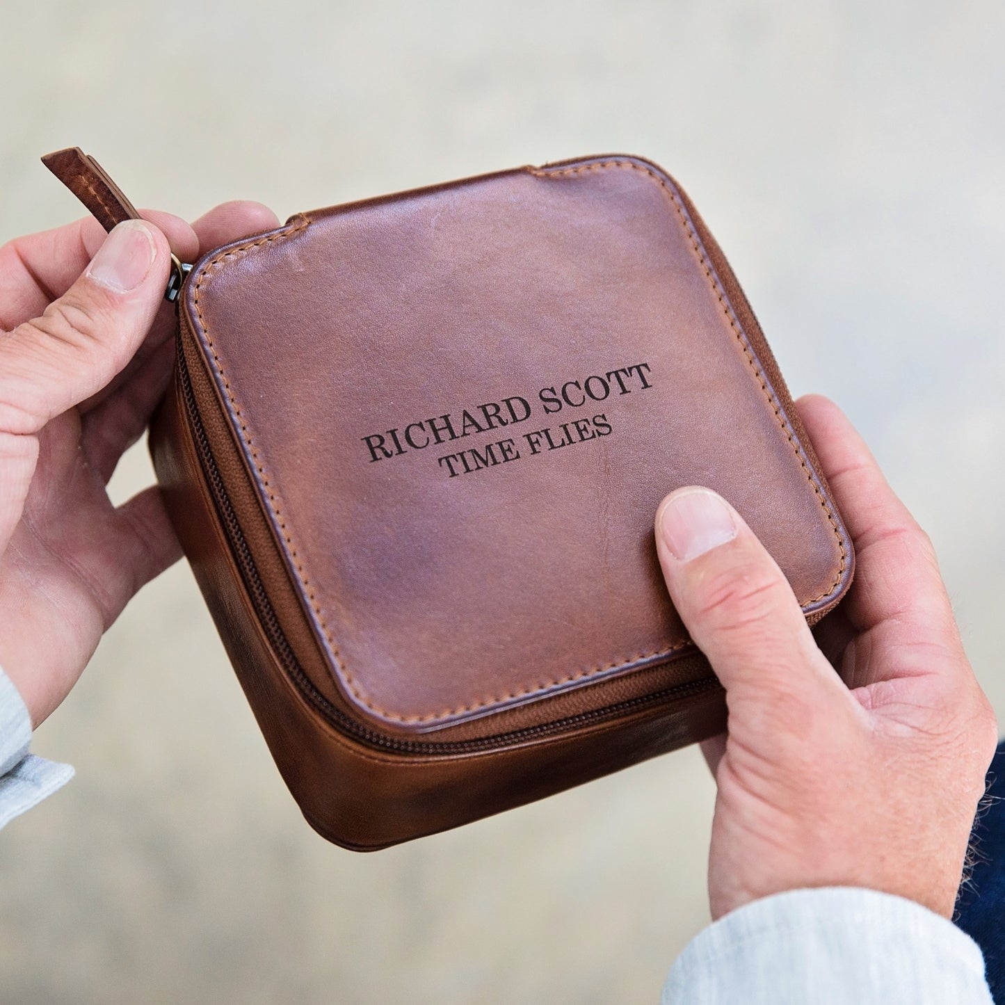 Square tan leather travel jewellery box with zip closure. Ideal for storing a watch, bracelets and rings whilst travelling. Personalise with a name, or message as a thoughtful 30th birthday gift for a jet set son.