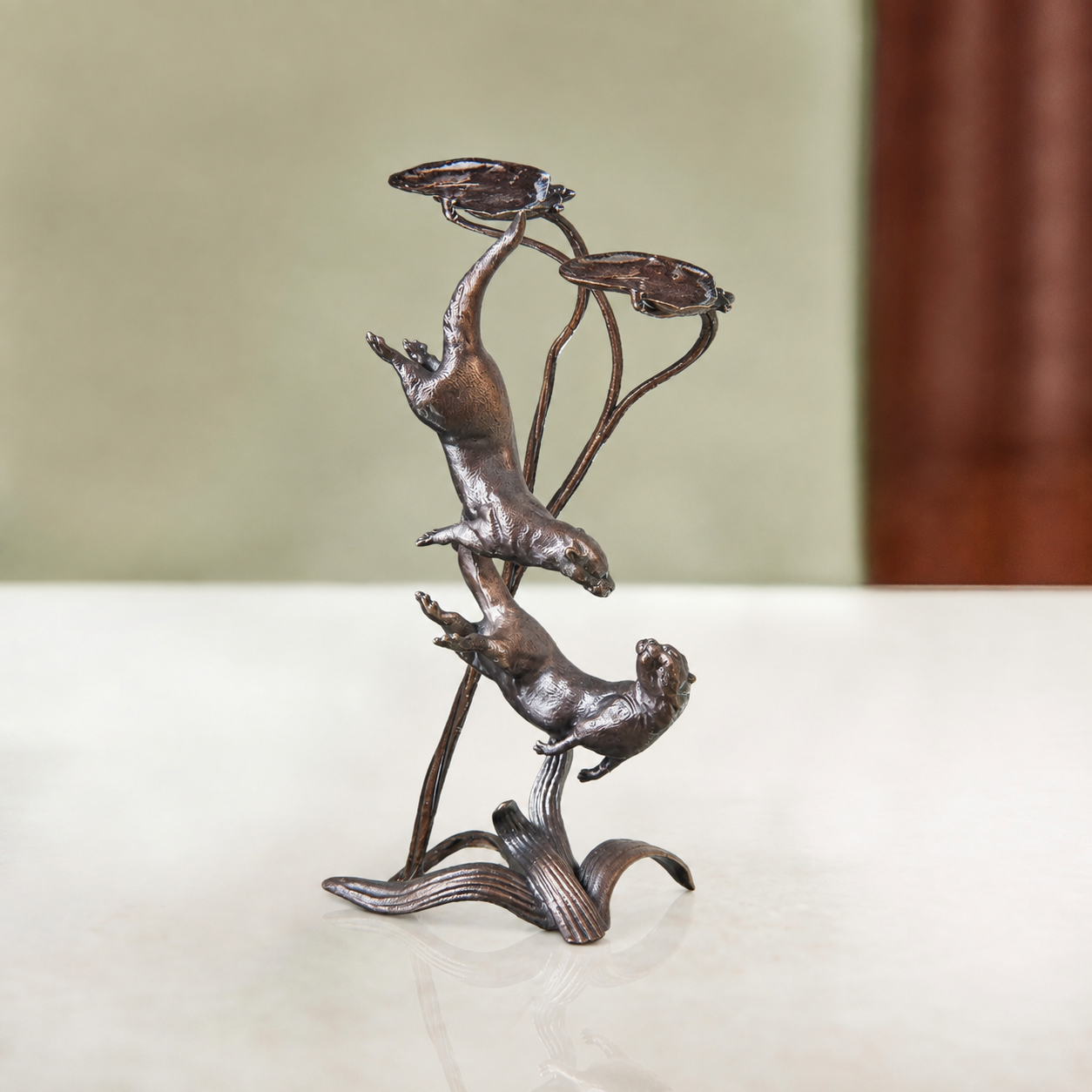 
                  
                    A bronze sculpture of two otters playing amongst the reeds and lily pads.
                  
                