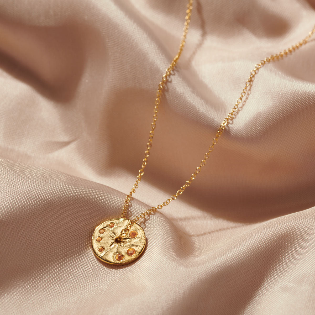 Gold disc pendant with set cirone gemstones for a November birthday gift.