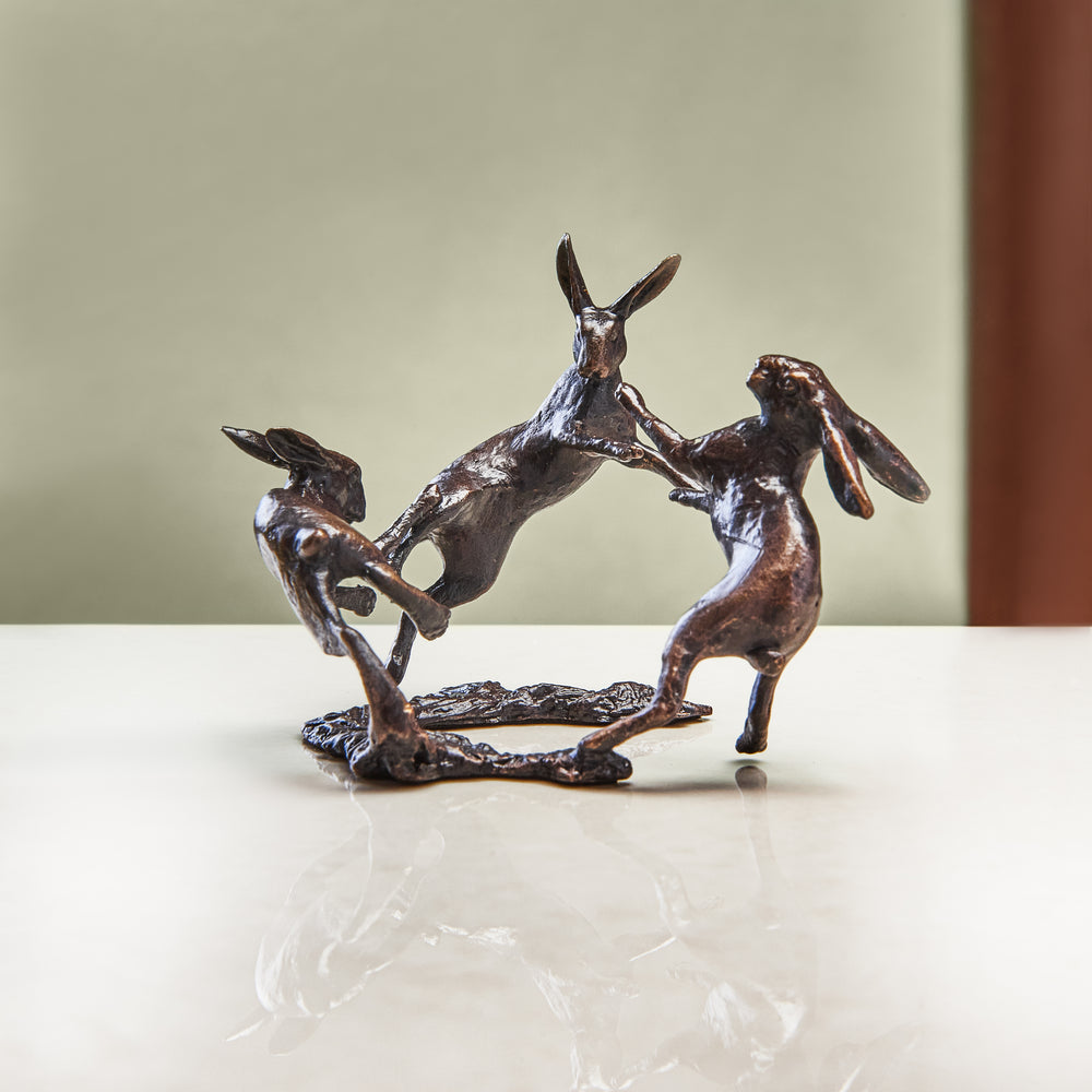 A miniature bronze figurine of three dancing hares that makes a thoughtful springtime birthday or bronze anniversary gift.
