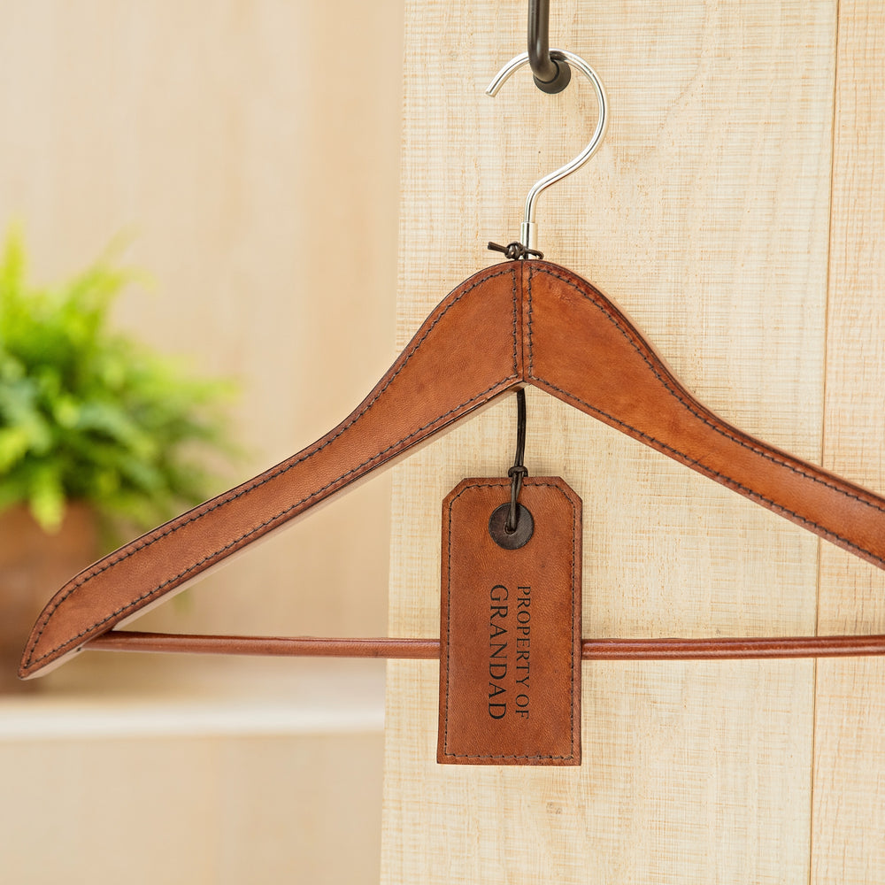 Personalised tan leather coat hanger for hanging suits, dresses or coats. Smooth handstitched finish protects clothes. Give as a thoughtful best man gift or unique new home present.