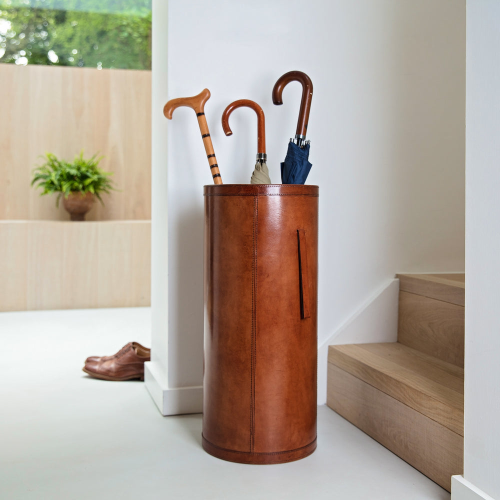 Classic cylindrical shaped tan leather umbrella stand with removable drip tray and carrying handles. Sturdy and timeless, add a personalised leather tag for a special birthday gift.