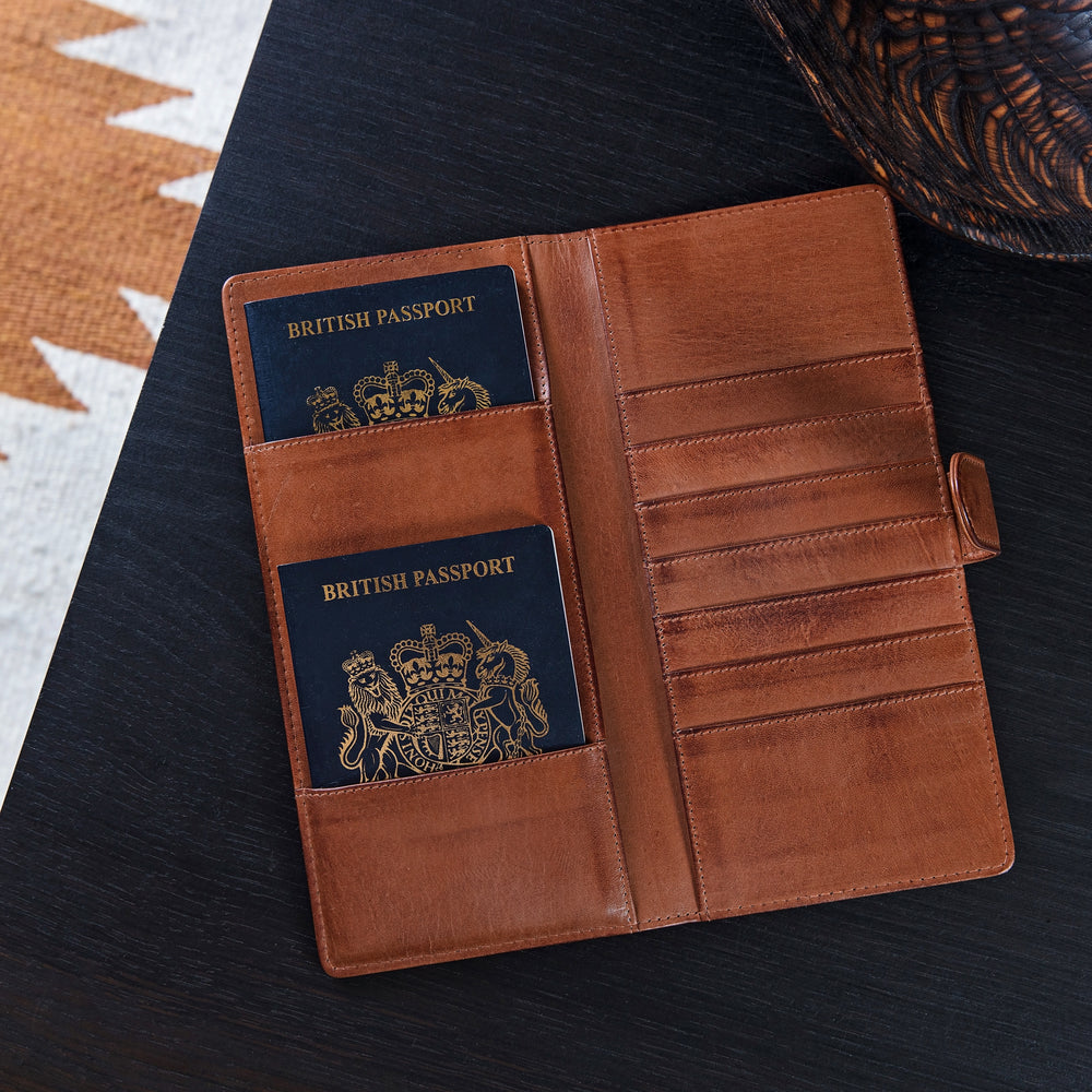 Leather travel wallet for passport and tickets. Made from soft tan leather, it closes with a secure strap and press stud and is RFID protected. Personalise for a unique father’s day gift.