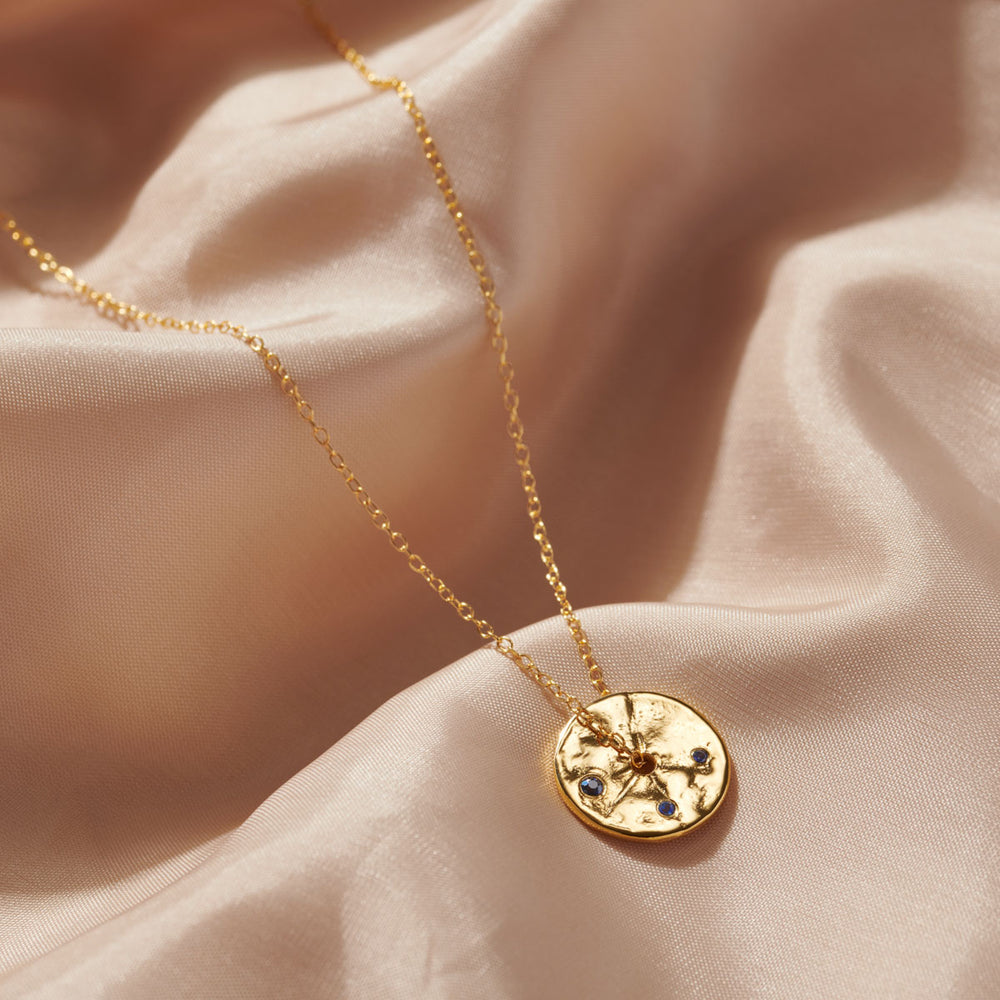 Birthstone gold disc necklace with small set sapphires on a gold chain. Gift to your daughter with a September birthday.